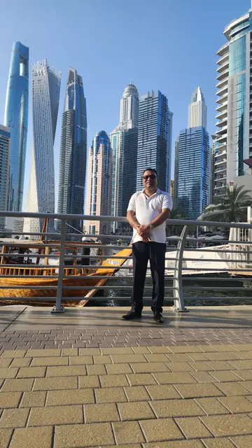 Abdul Kader Chowdhury at Dubai Marina, with high rise towers behind him